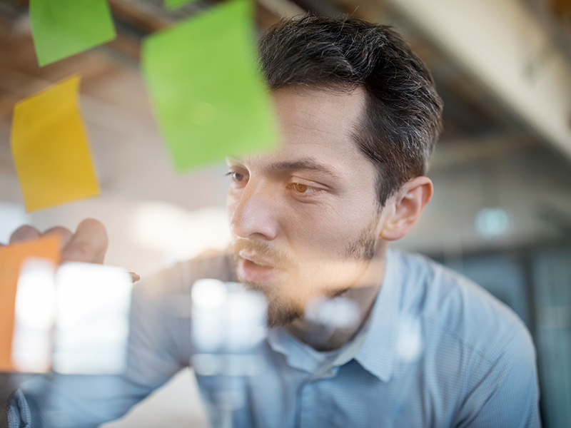 Young businessman writing on adhesive note