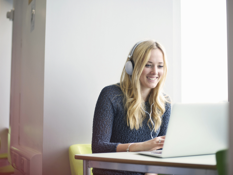 Young woman wearing headphones using laptop