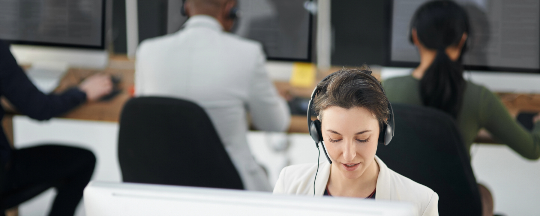 Young call centre agent working in an office with her colleagues