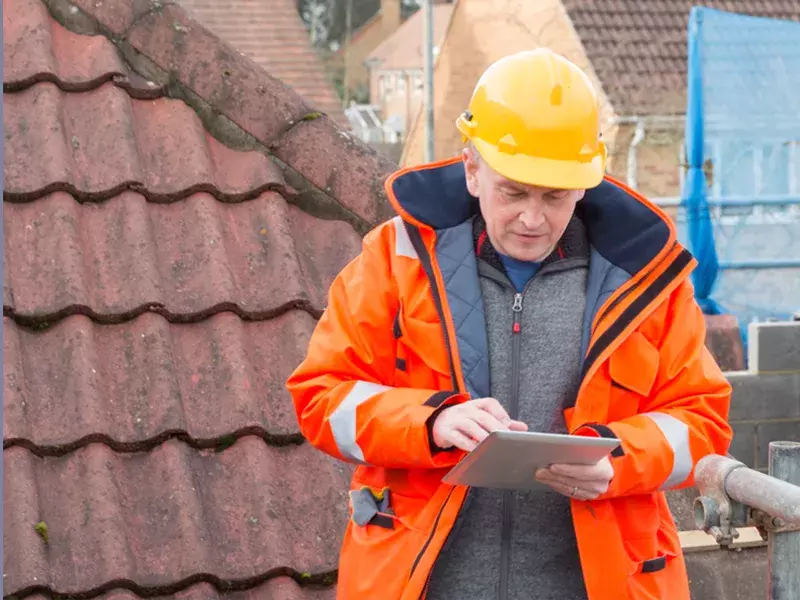 Man standing with a hard hat and tablet