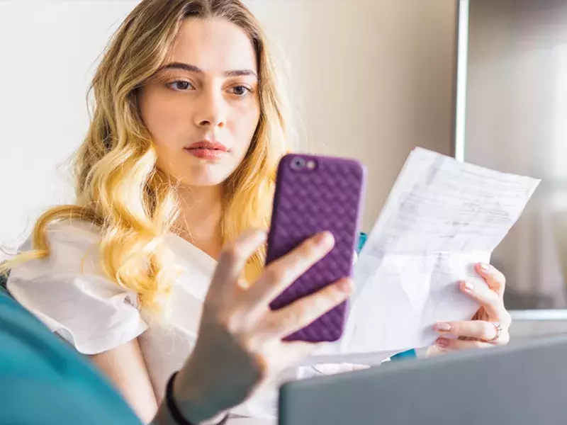 Woman using phone looking at bills