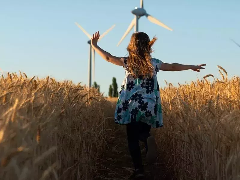 Girl running towards wind mills