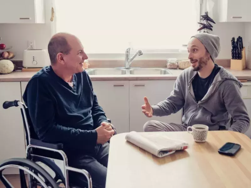 Healthcare-Man visiting a temporary disabled friend and having a coffee