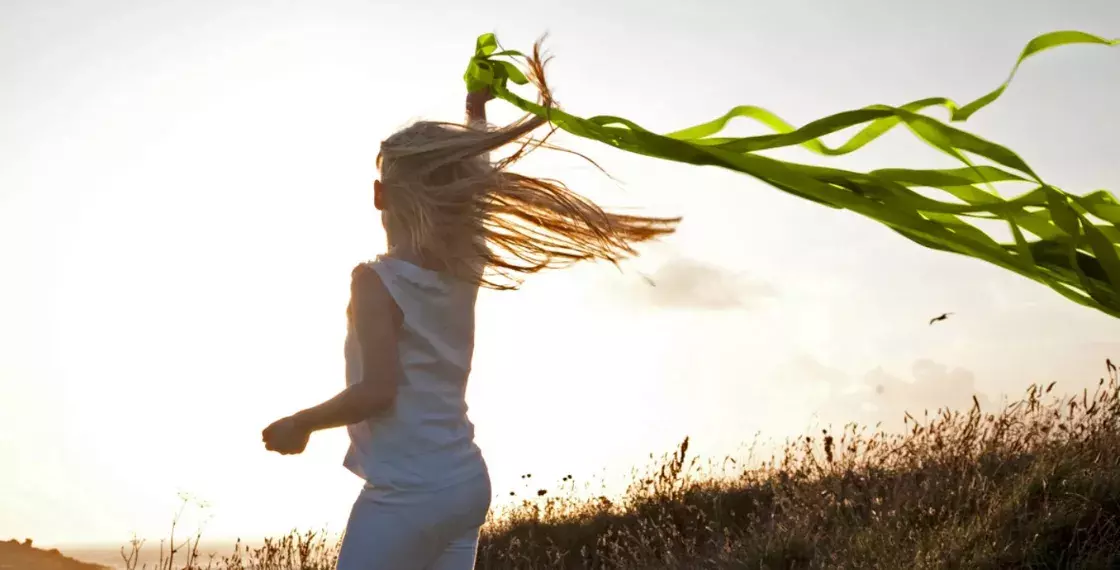 little girl running in field with ribbon